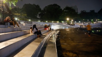 Warga beraktivitas saat malam hari di Taman Lapangan Banteng, Jakarta, Senin (9/6/2025). [Suara.com/Alfian Winanto]