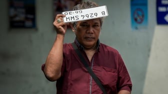 Seorang warga membawa plat nomor kendaraan usai melakukan pembayaran pajak kendaraan bermotor di Gedung Layanan Satu Atap Polda Metro Jaya, Jakarta, Senin (16/6/2025). [ANTARA FOTO/Sulthony Hasanuddin/tom]