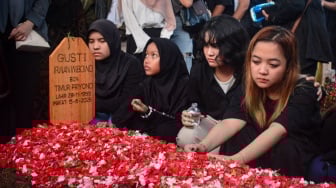 Anggota keluarga berdoa di samping pusara musisi Gusti Irwan Wibowo seusai pemakaman di TPU Jatisari 2, Bekasi, Minggu (15/6/2025). [ANTARA FOTO/Fathul Habib Sholeh/nym]