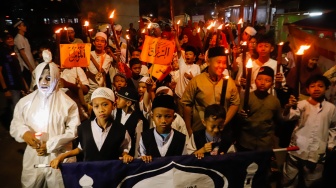 Sejumlah warga mengikuti pawai obor di RW 08 Kelurahan Menteng, Jakarta, Kamis (26/6/2025). [Suara.com/Alfian Winanto]