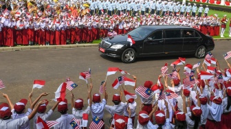 Sejumlah siswa SD menyambut kedatangan mobil yang membawa Presiden Prabowo Subianto dan Perdana Menteri Malaysia Anwar Ibrahim di Istana Merdeka, Jakarta, Jumat (27/6/2025). [ANTARA FOTO/Hafidz Mubarak A/app/nym.]
