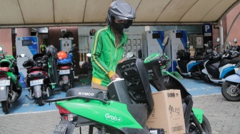 Pemilik kendaraan melakukan pengisian daya kendaraan listrik di SKPLU, Jakarta, Senin (7/7/2025). [Suara.com/Alfian Winanto]