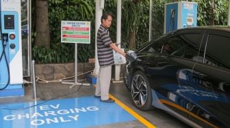 Pemilik kendaraan melakukan pengisian daya kendaraan listrik di SKPLU, Jakarta, Senin (7/7/2025). [Suara.com/Alfian Winanto]