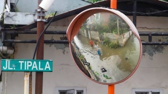 Warga beraktivitas di tengah banjir yang melanda di Jalan Tipala, Makasar, Jakarta Timur, Senin (7/7/2025). [Suara.com/Alfian Winanto]