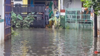 Warga beraktivitas di tengah banjir yang melanda di Jalan Tipala, Makasar, Jakarta Timur, Senin (7/7/2025). [Suara.com/Alfian Winanto]