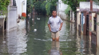 Warga beraktivitas di tengah banjir yang melanda di Jalan Tipala, Makasar, Jakarta Timur, Senin (7/7/2025). [Suara.com/Alfian Winanto]