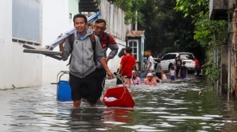 Warga beraktivitas di tengah banjir yang melanda di Jalan Tipala, Makasar, Jakarta Timur, Senin (7/7/2025). [Suara.com/Alfian Winanto]
