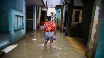 Warga beraktivitas di tengah banjir yang melanda pemukiman padat penduduk di kawasan Kebon Pala, Kampung Melayu, Jakarta, Selasa (8/7/2025). [Suara.com/Alfian Winanto]