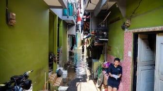 Warga beraktivitas di tengah banjir yang melanda pemukiman padat penduduk di kawasan Kebon Pala, Kampung Melayu, Jakarta, Selasa (8/7/2025). [Suara.com/Alfian Winanto]