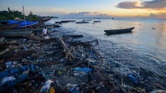 Nelayan mengeluarkan sampannya di antara sampah saat matahari terbit di Pantai Muara Siberut, Mentawai, Sumatera Barat, Selasa (8/7/2025). [ANTARA FOTO/Iggoy el Fitra/tom]