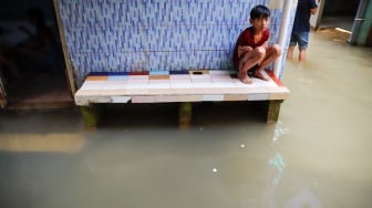 Warga beraktivitas di tengah banjir yang melanda pemukiman padat penduduk di kawasan Kebon Pala, Kampung Melayu, Jakarta, Selasa (8/7/2025). [Suara.com/Alfian Winanto]