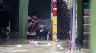 Warga beraktivitas di tengah banjir yang melanda pemukiman padat penduduk di kawasan Kebon Pala, Kampung Melayu, Jakarta, Selasa (8/7/2025). [Suara.com/Alfian Winanto]