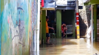 Warga beraktivitas di tengah banjir yang melanda pemukiman padat penduduk di kawasan Kebon Pala, Kampung Melayu, Jakarta, Selasa (8/7/2025). [Suara.com/Alfian Winanto]