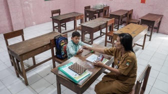 Guru mengajar seorang siswa kelas satu saat kegiatan Masa Pengenalan Lingkungan Sekolah Pendidikan (MPLS) di SD Negeri Kauman 27 Solo, Jawa Tengah, Senin (14/7/2025). [ANTARA FOTO/Mohammad Ayudha/rwa]