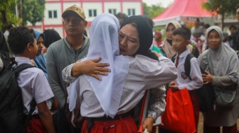 Siswa berpamitan pada orsng tuanya pada pembukaan masa pengenalan lingkungan sekolah (MPLS) di Sekolah Rakyat Menengah Pertama (SRMP) Sentra Handayani, Jakarta, Senin (14/7/2025). [Suara.com/Alfian Winanto]