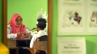 Guru memberikan pengajaran baca tulis kepada satu-satunya murid kelas 1 di SDN 1 Kendalrejo, Trenggalek, Jawa Timur, Senin (14/7/2025). [ANTARA FOTO/Destyan Sujarwoko/rwa]