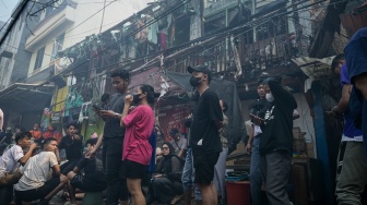 Sejumlah warga menyaksikan proses pendinginan di lokasi kebakaran permukiman penduduk di Duri Utara, Tambora, Jakarta, Senin (21/7/2025). [Suara.com/Alfian Winanto]
