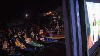 Sejumlah warga menonton bioskop terapung dari perahunya di Desa Muara Enggelam, Muara Wis, Kutai Kartanegara, Kalimantan Timur, Selasa (22/7/2025). [ANTARA FOTO/M Risyal Hidayat/tom]

