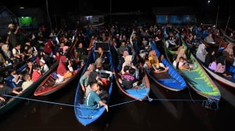 Sejumlah warga menonton bioskop terapung dari perahunya di Desa Muara Enggelam, Muara Wis, Kutai Kartanegara, Kalimantan Timur, Selasa (22/7/2025). [ANTARA FOTO/M Risyal Hidayat/tom]