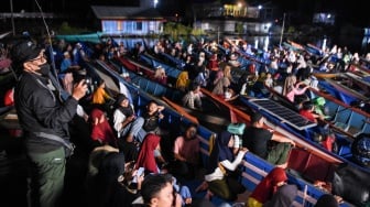 Sejumlah warga bersiap untuk menonton bioskop terapung dari perahunya di Desa Muara Enggelam, Muara Wis, Kutai Kartanegara, Kalimantan Timur, Selasa (22/7/2025). [ANTARA FOTO/M Risyal Hidayat/tom]