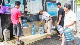 Warga mengisi air minum gratis di kawasan Rawamangun, Jakarta, Kamis (24/7/2025). [Suara.com/Alfian Winanto]
