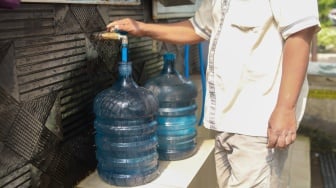 Warga mengisi air minum gratis di kawasan Rawamangun, Jakarta, Kamis (24/7/2025). [Suara.com/Alfian Winanto]
