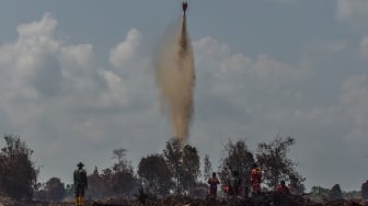 Sejumlah petugas menyaksikan helikopter water bombing VN8416 milik BNPB menjatuhkan air saat memadamkan api kebakaran hutan dan lahan (karhutla) di lahan gambut Desa Gambut Jaya, Muaro Jambi, Jambi, Rabu (30/7/2025). [ANTARA FOTO/Wahdi Septiawan/foc]