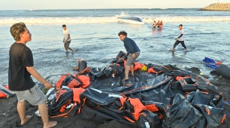 Warga berusaha menarik barang-barang dari kapal cepat Bali Dolphin Cruise 2 yang mengalami kecelakaan ke tepi pantai di kawasan Sanur, Denpasar, Bali, Selasa (5/8/2025). [ANTARA FOTO/Fikri Yusuf/YU]