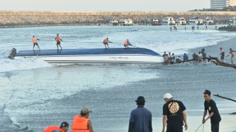 Warga berusaha menarik kapal cepat Bali Dolphin Cruise 2 ke tepi pantai di kawasan Sanur, Denpasar, Bali, Selasa (5/8/2025). [ANTARA FOTO/Fikri Yusuf/YU]
