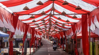 Pengendara sepeda motor melintas di jalan yang bagian atasnya dihiasi kain merah putih di Kampung Cibahong, Desa Sukamenak, Kecamatan Sukarame, Kabupaten Tasikmalaya, Jawa Barat, Rabu (6/8/2025). [ANTARA FOTO/Adeng Bustomi/tom]