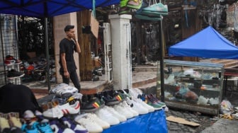 Pedagang menjajakan dagangannya pada lokasi bekas kebakaran di Pasar Taman Puring, Jakarta, Rabu (13/8/2025). [Suara.com/Alfian Winanto]