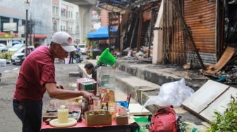 Pedagang menjajakan dagangannya pada lokasi bekas kebakaran di Pasar Taman Puring, Jakarta, Rabu (13/8/2025). [Suara.com/Alfian Winanto]