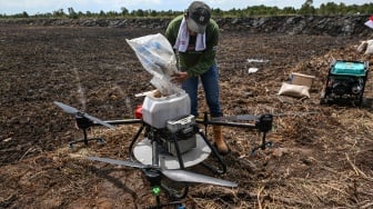 Pekerja menuangkan benih padi di drone untuk ditebar saat tanam perdana di lokasi cetak sawah rakyat (CSR) di kawasan Bati-Bati, Tanah Laut, Kalimantan Selatan, Selasa (12/8/2025). [ANTARA FOTO/Hafidz Mubarak A/YU]