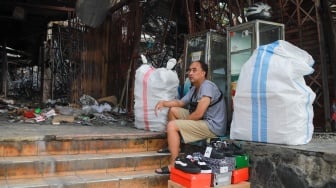 Pedagang menjajakan dagangannya pada lokasi bekas kebakaran di Pasar Taman Puring, Jakarta, Rabu (13/8/2025). [Suara.com/Alfian Winanto]