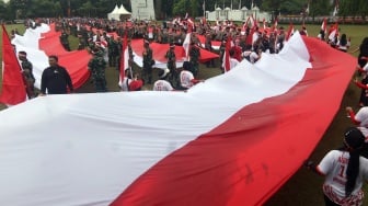 Sejumlah personel TNI dan Polri membentangkan Bendera Merah Putih dalam Kirab Merah Putih di Lingkar Stadion Pakansari, Kabupaten Bogor, Jawa Barat, Kamis (14/8/2025). [ANTARA FOTO/Yulius Satria Wijaya/nym]
