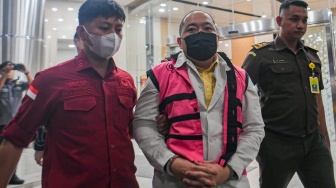 Tersangka kasus dugaan tindak pidana korupsi PT Sritex Iwan Kurniawan Lukminto (tengah) berjalan menuju mobil tahanan usai ditetapkan sebagai tersangka di Kejaksaan Agung, Jakarta, Rabu (13/8/2025). [ANTARA FOTO/Muhammad Adimaja/nym]