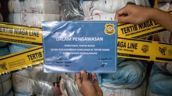 Petugas menempelkan tanda pengawasan pada barang bukti pakaian bekas saat ekspose hasil pengawasan barang impor tidak sesuai ketentuan oleh Kementerian Perdagangan di Bojongsoang, Kabupaten Bandung, Jawa Barat, Selasa (19/8/2025). [ANTARA FOTO/Abdan Syakura/rwa]