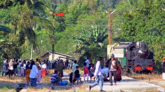 Warga menyambut lokomotif E1060 Mak Itam saat membawa wisatawan di Stasiun Muaro Kalaban Sawahlunto, Sumatera Barat, Selasa (26/8/2025). [ANTARA FOTO/Iggoy el Fitra/nym]