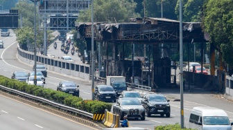 Kendaraan melintas di samping Gerbang Tol Pejompongan pasca terbakar di Jakarta, Senin (1/9/2025). [Suara.com/Alfian Winanto]
