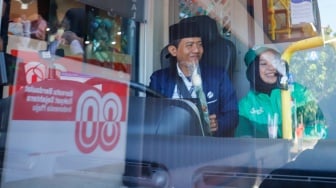 Pengemudi ojek online (ojol) membagikan bunga ke pengguna jalan saat aksi damai di Jalan Merdeka Selatan, Jakarta, Selasa (2/9/2025). [Suara.com/Alfian Winanto]