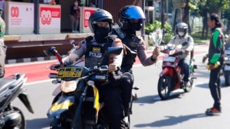 Pengemudi ojek online (ojol) membagikan bunga ke pengguna jalan saat aksi damai di Jalan Merdeka Selatan, Jakarta, Selasa (2/9/2025). [Suara.com/Alfian Winanto]