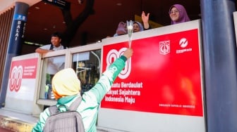Pengemudi ojek online (ojol) membagikan bunga ke pengguna jalan saat aksi damai di Jalan Merdeka Selatan, Jakarta, Selasa (2/9/2025). [Suara.com/Alfian Winanto]