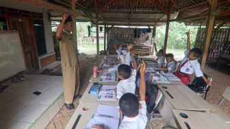 Siswa kelas dua SDN Tegal Benteng belajar di halaman rumah warga di Desa Babakan Raden, Cariu, Kabupaten Bogor, Jawa Barat, Senin (8/9/2025). [ANTARA FOTO/Yulius Satria Wijaya/rwa]