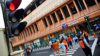 Pejalan kaki menyeberang pada pelican crossing di depan Stasiun Cikini, Jakarta, Senin (15/9/2025). [Suara.com/Alfian Winanto]