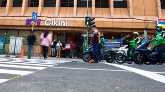Pejalan kaki menyeberang pada pelican crossing di depan Stasiun Cikini, Jakarta, Senin (15/9/2025). [Suara.com/Alfian Winanto]
