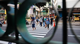 Pejalan kaki menyeberang pada pelican crossing di depan Stasiun Cikini, Jakarta, Senin (15/9/2025). [Suara.com/Alfian Winanto]