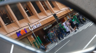 Pejalan kaki menyeberang pada pelican crossing di depan Stasiun Cikini, Jakarta, Senin (15/9/2025). [Suara.com/Alfian Winanto]