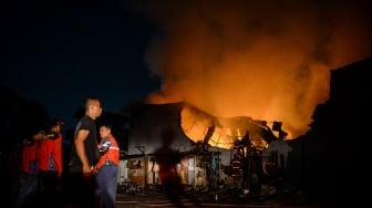 Warga melihat petugas damkar berusaha memadamkan api yang membakar pabrik konstruksi di Serpong Utara, Kota Tangerang Selatan, Banten, Senin (15/9/2025). [ANTARA FOTO/Putra M. Akbar/nz]