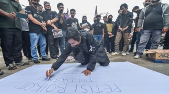 Salah seorang jurnalis yang tergabung dalam Koalisi Anti Pembungkaman Demokrasi menulis petisi saat melakukan aksi diam di Mapolda Jambi, Jambi, Rabu (17/9/2025). [ANTARA FOTO/Wahdi Septiawan/bar]