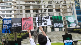 Peserta aksi yang tergabung dalam Koalisi Masyarakat Sipil Untuk Reformasi Sektor Keamanan mengangkat poster saat mengikuti aksi di depan Gedung Mahkamah Konstitusi (MK), Jakarta, Rabu (17/9/2025). [Suara.com/Alfian Winanto]